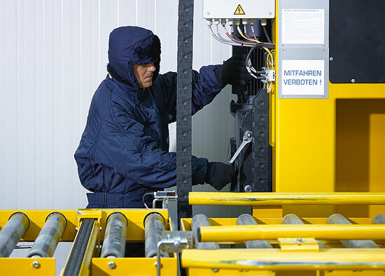 A Bischof employee maintains the stacker crane in a cold suit A Bischof employee maintains the stacker crane in a cold suit