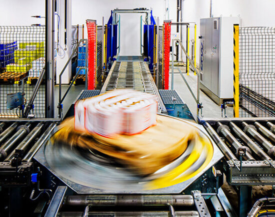 Ein Paket bewegt sich schnell auf einem Förderband in einem modernen Distributionszentrum.