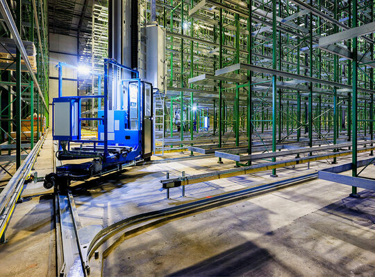Regalbediengeräte auf Schienen in einer große Lagerhalle Regalbediengeräte auf Schienen in einer große Lagerhalle