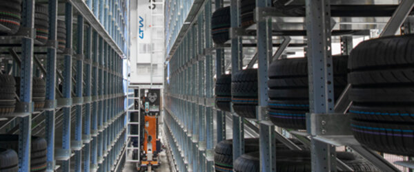 Regalbediengerät im Hochregallager, umgeben von eingelagerten Reifen