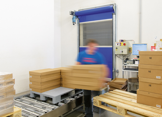 An employee of Hermes is loading a pallet that is standing on the conveyor system