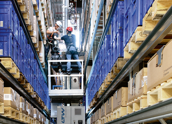 Two LTW employees stand on a stacker crane and make a retrofit